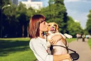 Νέα γυναίκα φιλάει σκύλο σε πάρκο χωρίς συμπτώματα αλλεργικής ρινίτιδας από τρίχες ζώων ή γύρη χάρη στην ομοιοπαθητική θεραπεία στην Αθήνα