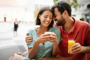 Χαρούμενο ζευγάρι απολαμβάνει στιγμές οικειότητας σε καφετέρια, συμβολίζοντας την αποκατάσταση της σεξουαλικής αυτοπεποίθησης και την ξεκούραστη σύνδεση μετά από ομοιοπαθητική θεραπεία για ψυχογενή στυτική δυσλειτουργία στην Αθήνα