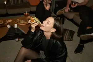 Νέα γυναίκα απολαμβάνει burger σε πάρτυ χωρίς φόβο για συμπτώματα ευερέθιστου εντέρου χάρη στην ομοιοπαθητική θεραπεία στην Αθήνα