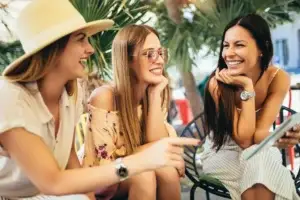 Τρεις γυναίκες απολαμβάνουν καφέ σε υπαίθριο cafe με χαμόγελα - ομοιοπαθητική για επιχείλιο έρπητα