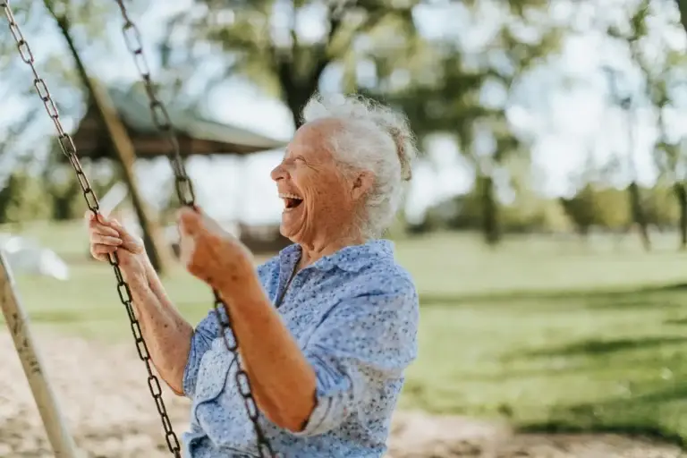 Ηλικιωμένη γυναίκα γελάει κάνοντας κούνια, δείχνοντας τη χαρά και την κινητικότητα μετά από ομοιοπαθητική θεραπεία για οστεοαρθρίτιδα.