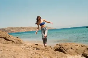 Νεαρή γυναίκα περπατά ξυπόλητη στα βράχια στην παραλία - Ανάκτηση ισορροπίας & κινητικότητας στη Σκλήρυνση Κατά Πλάκας