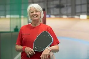 Ενεργή γυναίκα που παίζει pickleball και χρησιμοποιεί ομοιοπαθητική για τη διαχείριση της οσφυαλγίας.