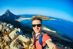 Άνδρας απολαμβάνει πεζοπορία σε ελληνικό τοπίο με θέα τη θάλασσα - ενεργός τρόπος ζωής και σωστή ενυδάτωση για πρόληψη νεφρολιθίασης