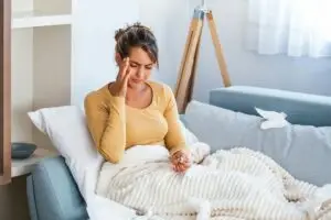 Γυναίκα με έντονα συμπτώματα ιγμορίτιδας και κόπωση ξαπλωμένη στον καναπέ - Θεραπεία Kali Bichromicum